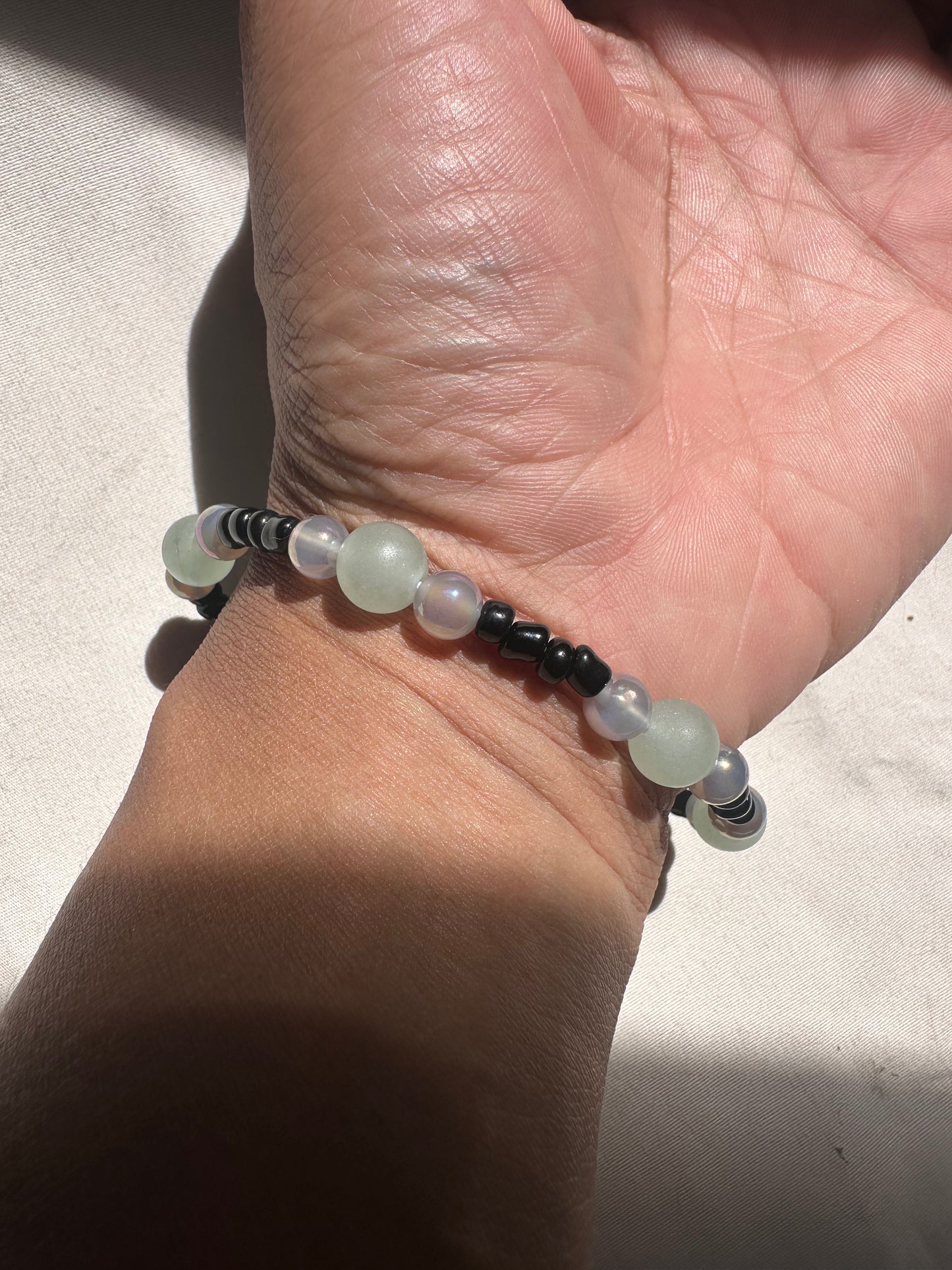 Close-up of a hand wearing a beaded bracelet on a light background